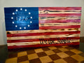 Large flat stained wooden Betsy Ross flag with 13 stars, 1776, and We the People wood-burned script
